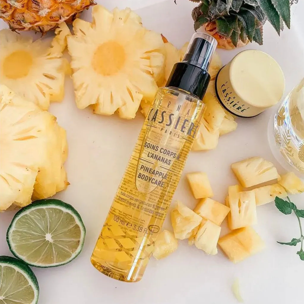 Pump bottle of Bernard Cassiere stretchmark and firmness body oil laying on cut up pineapple pieces 